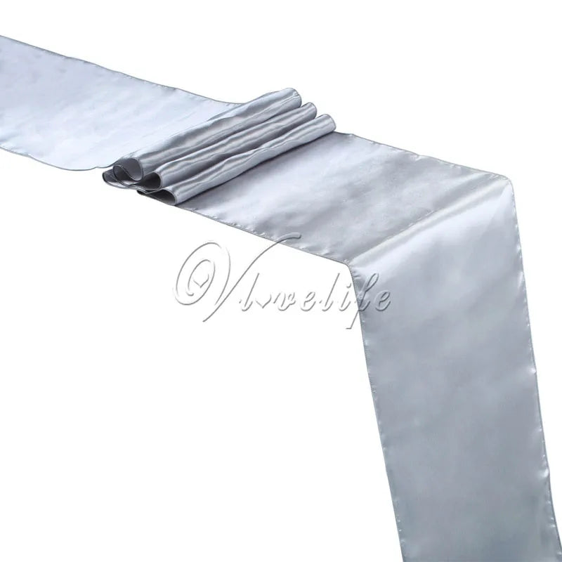 A silver satin table runner draped and folded for weddings and events.