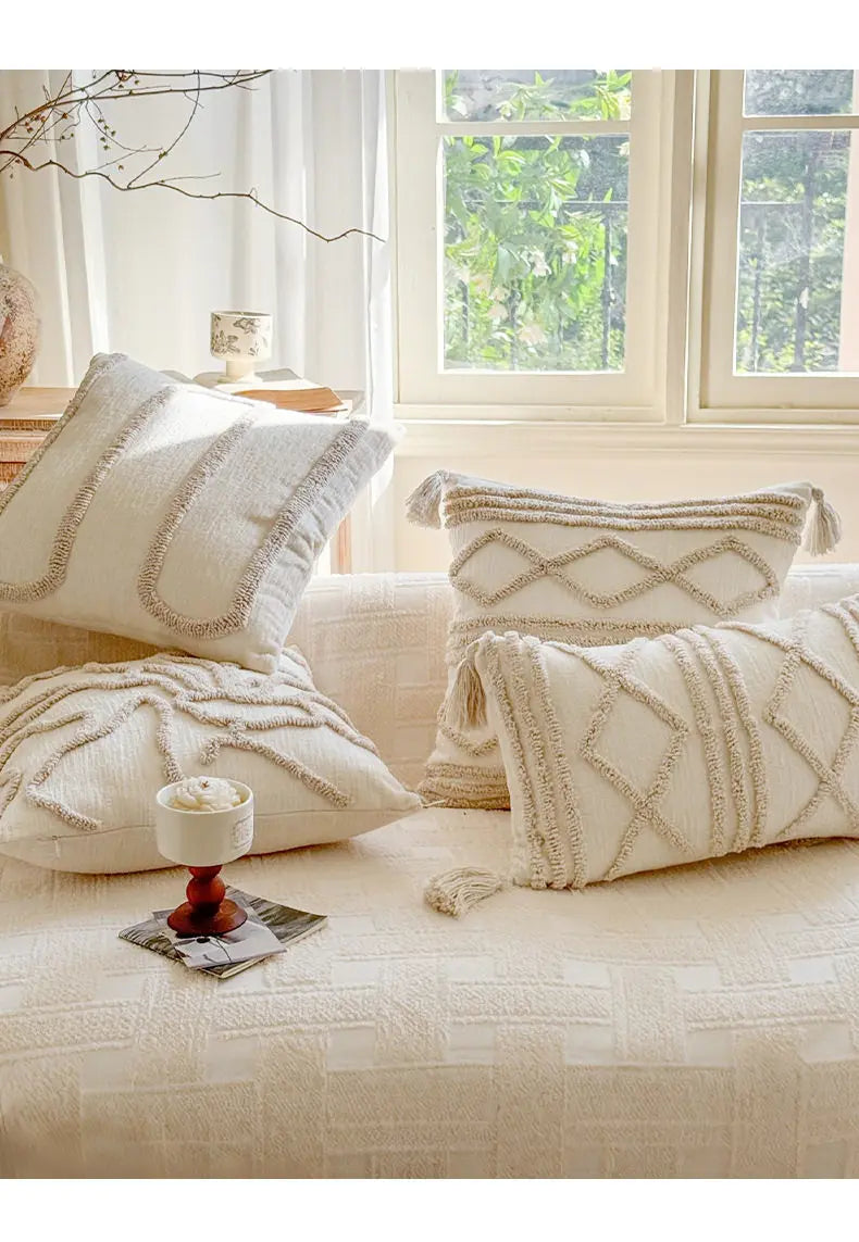 A collection of cream and beige bohemian knit pillow covers displayed on a light-colored sofa.