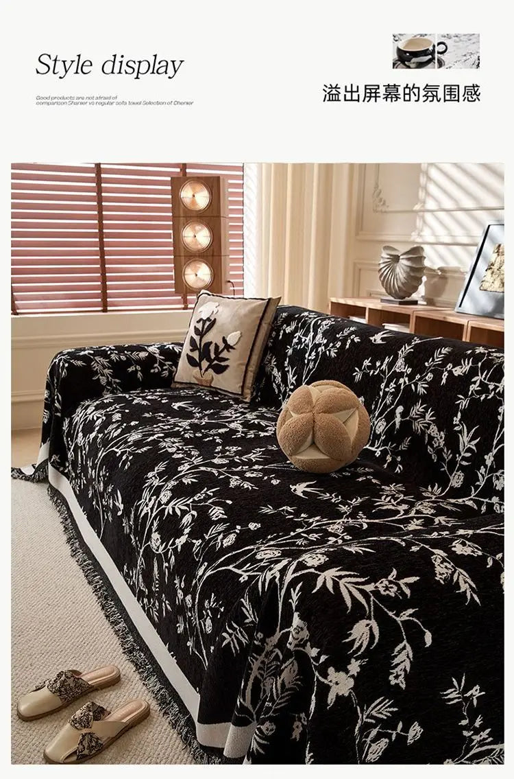 A black and white floral patterned chenille sofa slipcover displayed on a light-colored sofa with natural light.