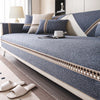A close-up of a linen sofa cover featuring blue and beige tones with decorative trim, placed on a wooden floor.