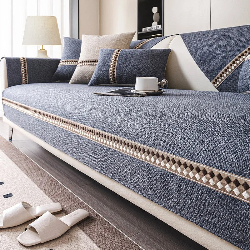 A close-up of a linen sofa cover featuring blue and beige tones with decorative trim, placed on a wooden floor.