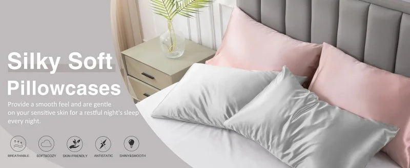 A set of silky soft pink and white pillowcases displayed on a bed with a wooden nightstand.
