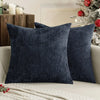 A dark navy blue chenille pillow cover with a textured weave resting on a light-colored sofa.