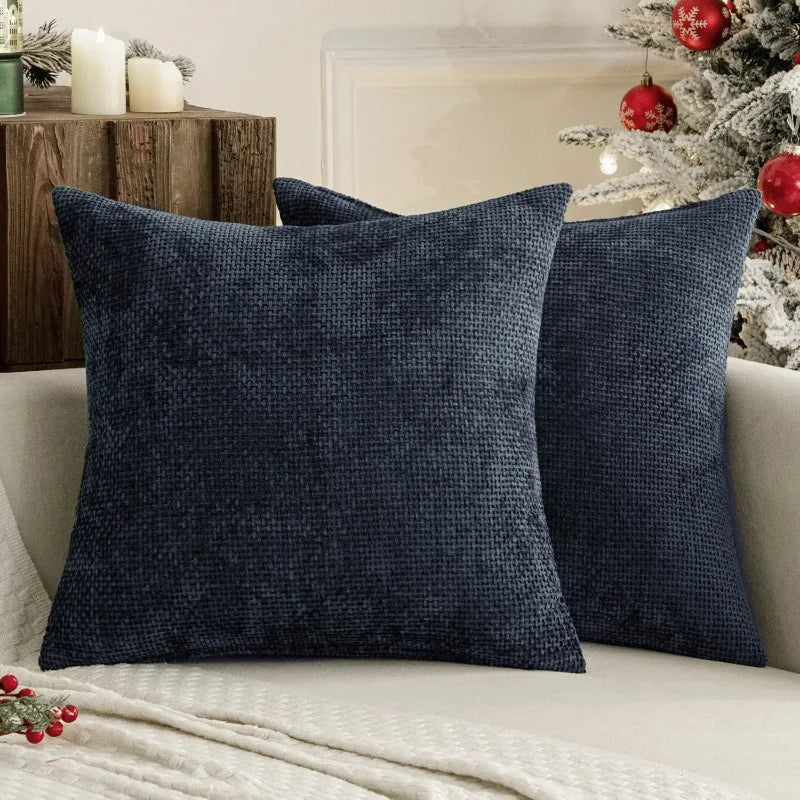 A dark navy blue chenille pillow cover with a textured weave resting on a light-colored sofa.