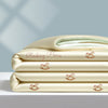 A stack of cream-colored cooling summer quilts embroidered with small pink rocking horses.