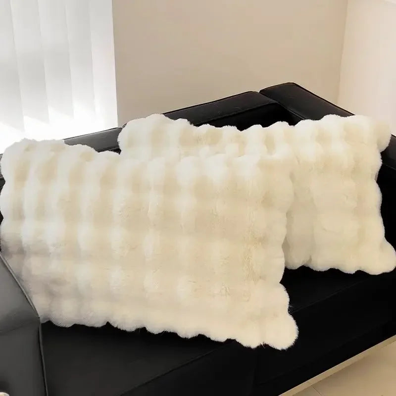 A white, fluffy quilted pillow cover is displayed on a dark surface.