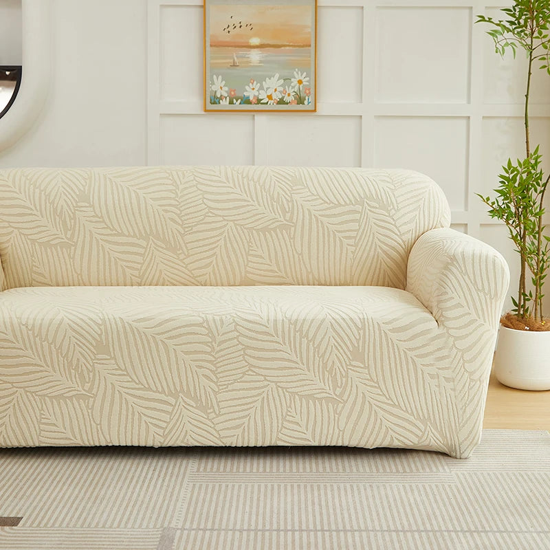 A beige sofa slipcover featuring a woven jacquard leaves pattern in a light neutral tone.