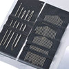 A set of stainless steel hand sewing needles arranged in rows on a dark surface.