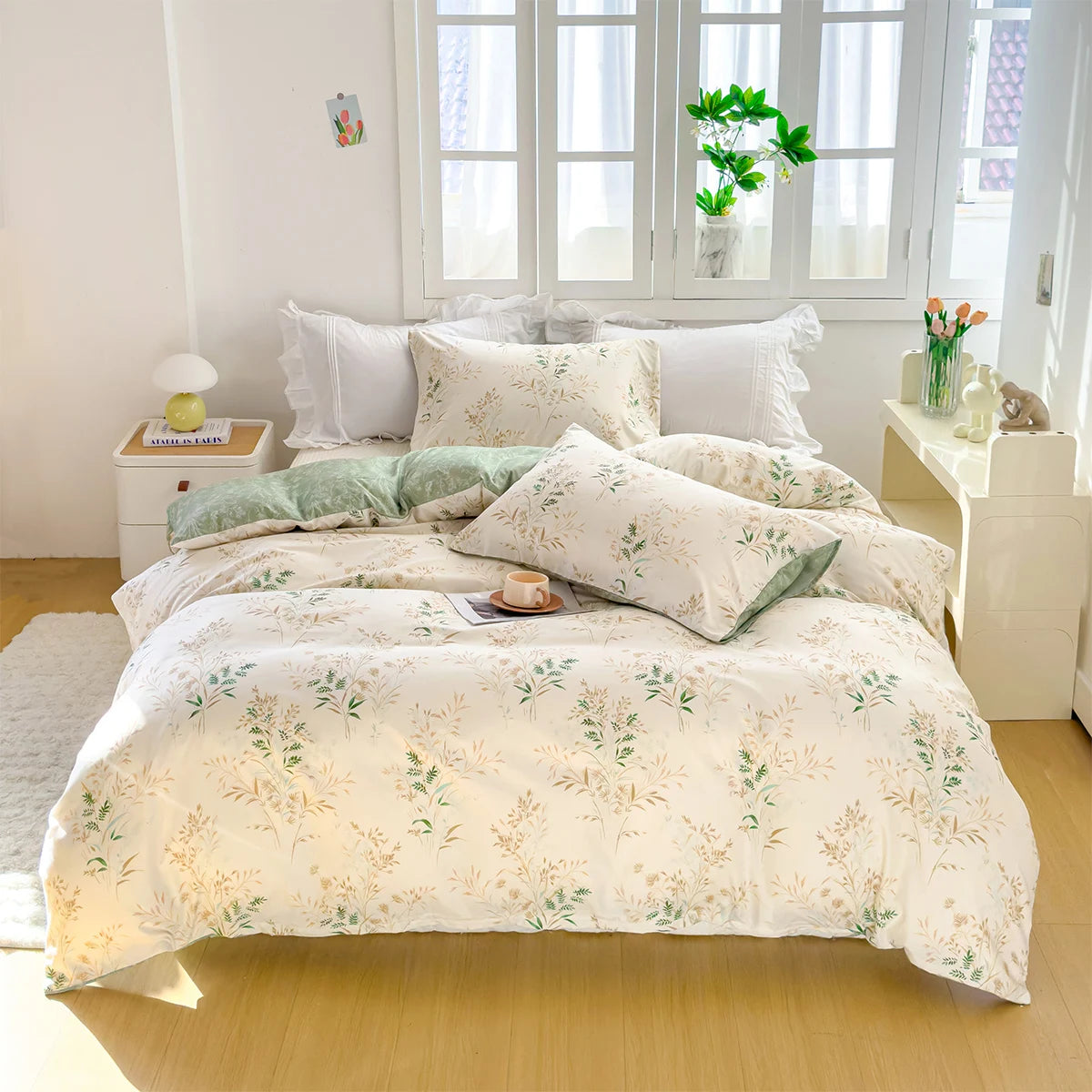 A white duvet cover set with a floral pattern featuring green leaves and yellow accents displayed on a bed.