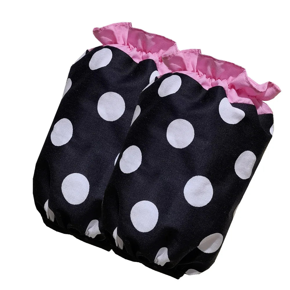 A black polka dot ruffle apron with pink trim and pockets.