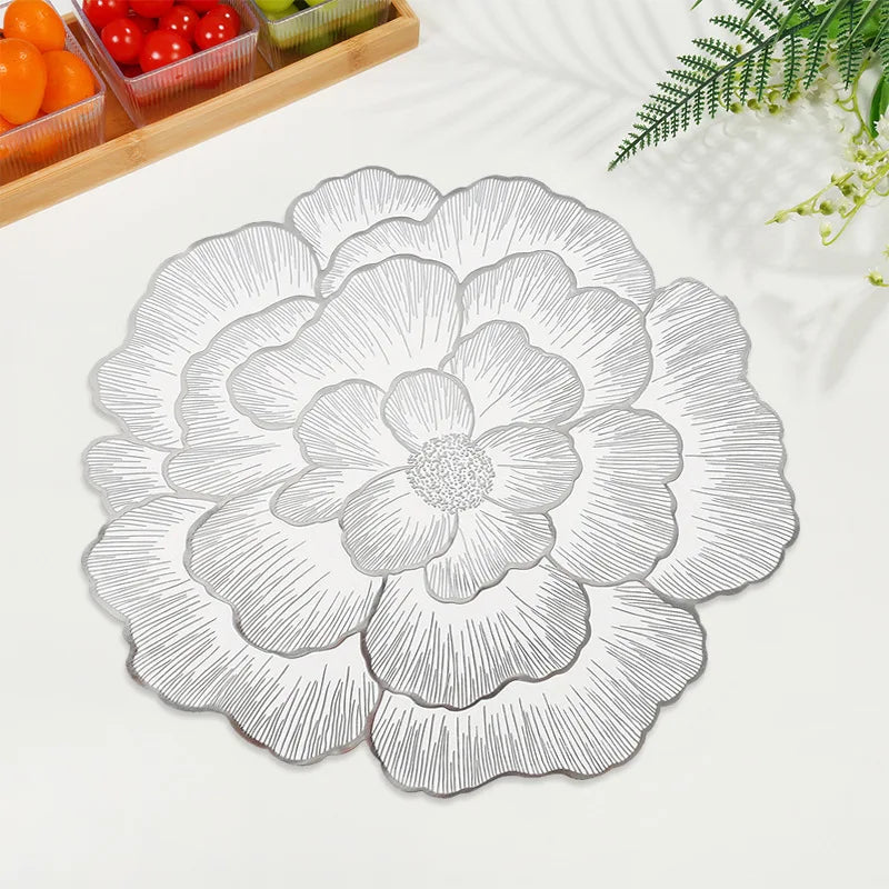 A round, gray-toned peony flower pattern coaster is shown on a white surface next to fresh tomatoes and a green pepper.