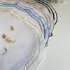 Elegant embroidered cotton linen placemat featuring blue and gold geometric patterns on white fabric