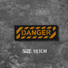 A black hook and loop badge with the word DANGER in yellow text on a gray textured background.