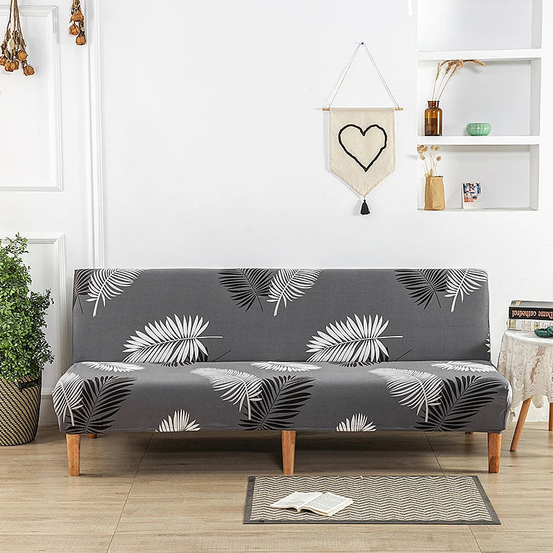 A gray sofa with black and white geometric leaf print slipcovers sits in a bright room.