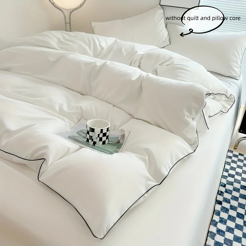 A white duvet cover set with a quilted texture is displayed on a bed, featuring a decorative pillow and a small framed item.