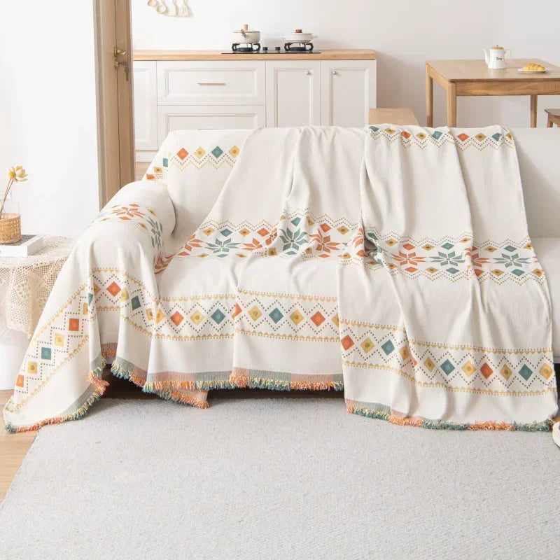 A cream and terracotta bohemian accent sofa cover draped over a light-colored sofa.