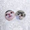 A pair of tinplate pin brooches featuring cute cat faces with expressive eyes and pink noses.