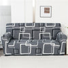 A gray and white patterned stretch floral elastic sofa cover displayed on a white floor.