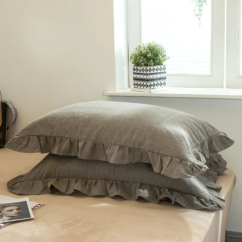 A set of two soft plaid washed cotton pillowcases with ruffled edges resting on a light surface.