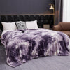 A purple and white tie-dye flannel fleece throw blanket draped over a bed in a modern bedroom.
