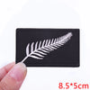 Black embroidered patch featuring a white feather design on a fabric background