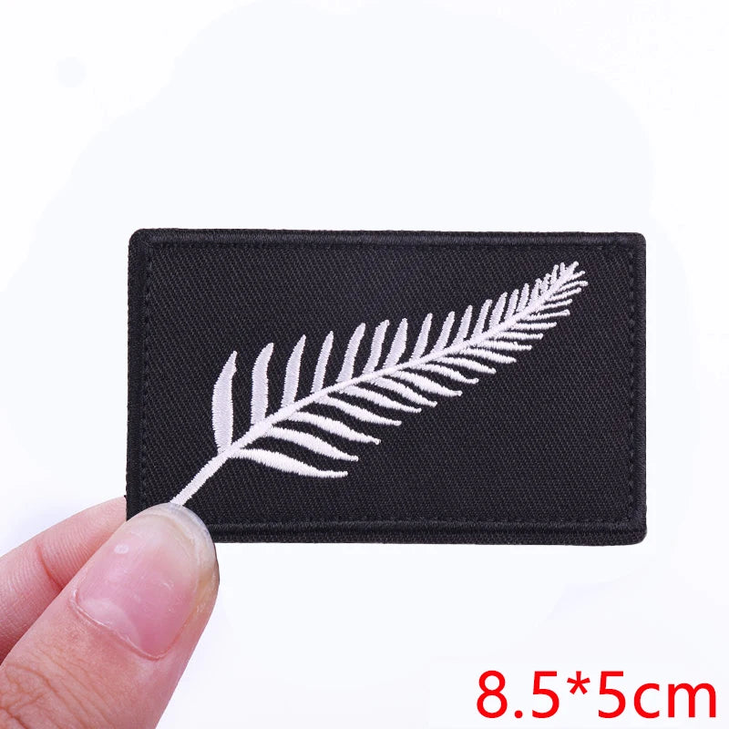 Black embroidered patch featuring a white feather design on a fabric background