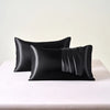 Black satin pillowcase with an envelope closure, displayed on a white surface.