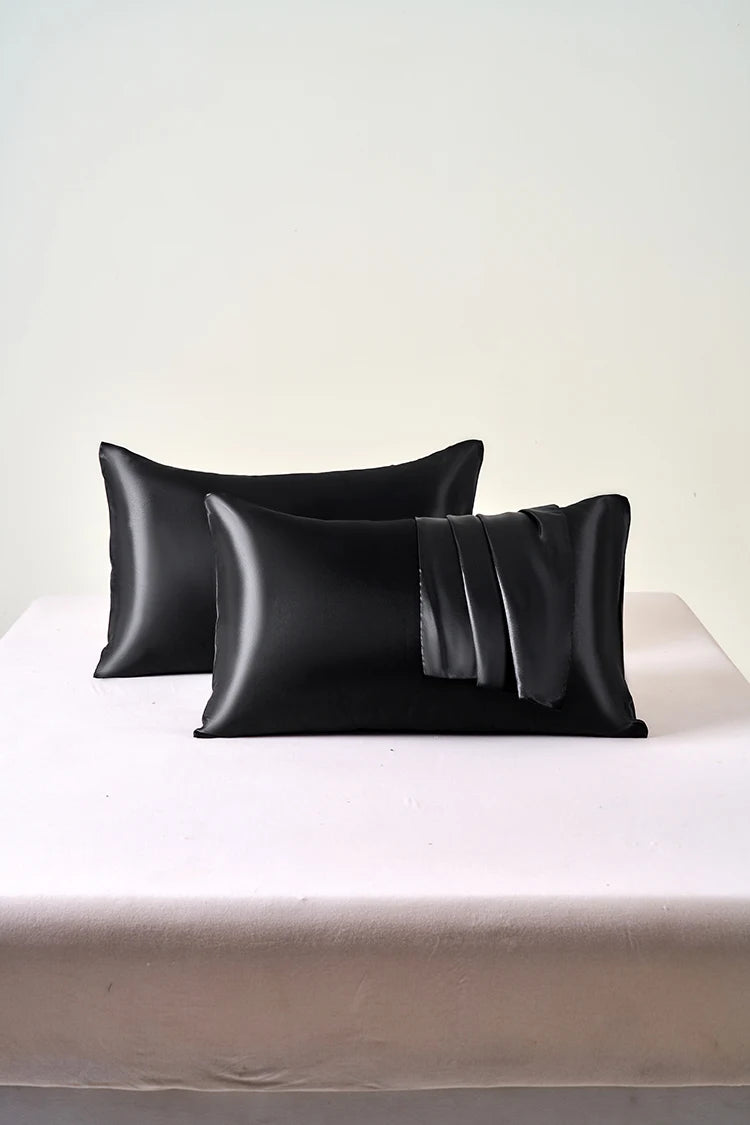 Black satin pillowcase with an envelope closure, displayed on a white surface.