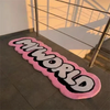 A pink and black cartoon mat with the word MYWORLD is placed on a dark tiled floor.