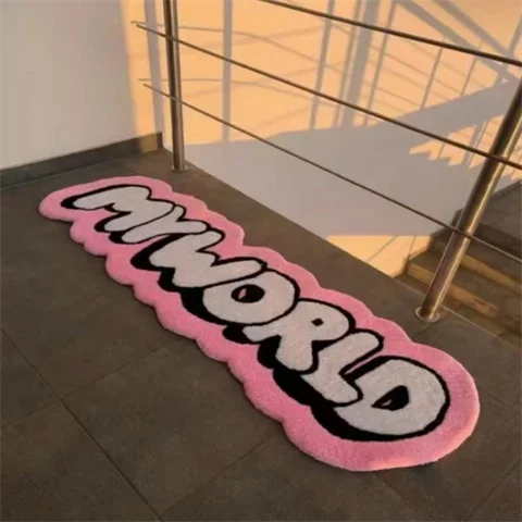 A pink and black cartoon mat with the word MYWORLD is placed on a dark tiled floor.