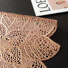 A detailed, intricately cut leaf-shaped placemat or table runner made of light brown, textured material.