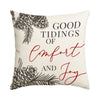 A cream-colored pillow featuring red script text that reads Good Tidings of Comfort and Joy, with dark foliage designs.