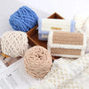 Three skeins of soft beige and blue chenille knitting yarn displayed on a wooden tray.