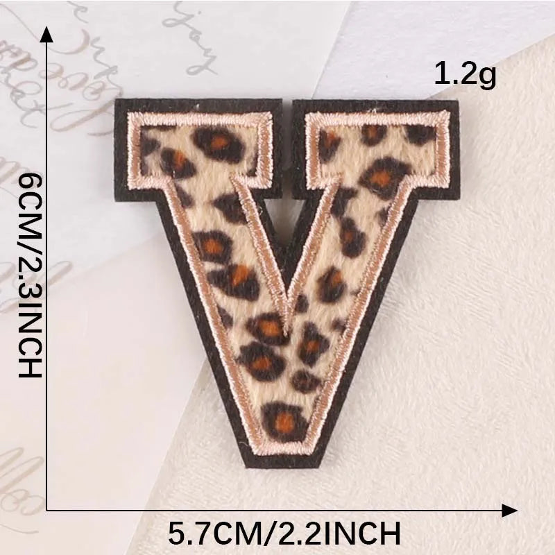 Iron-on patch shaped like the letter V in leopard print on a white fabric background