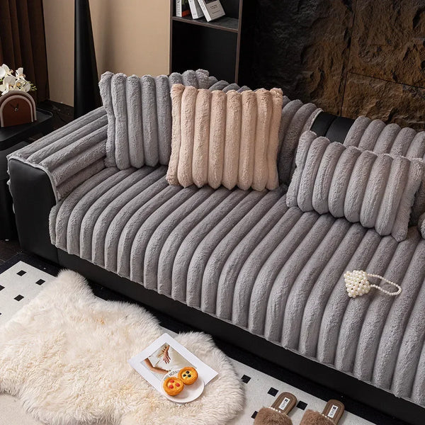 A gray thickened plush sofa seat cushion with vertical tufting rests on a white faux fur rug.
