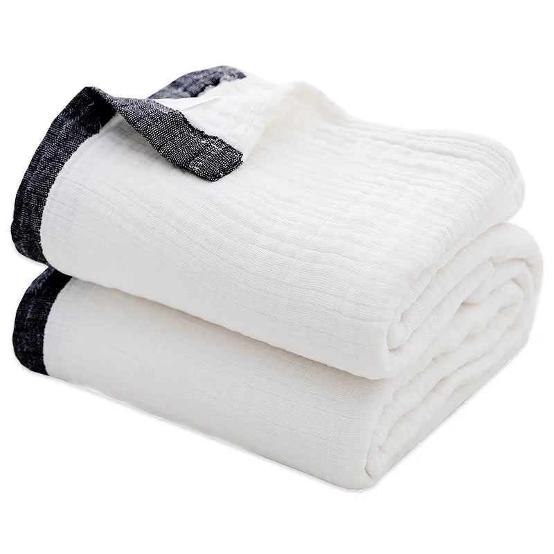 A stack of white and black muslin throw blankets rolled up.