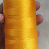 A spool of bright orange high tenacity polyester sewing thread is held in a hand.