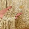 A hand is holding a bundle of gold metallic beaded string curtains for home and party decor.