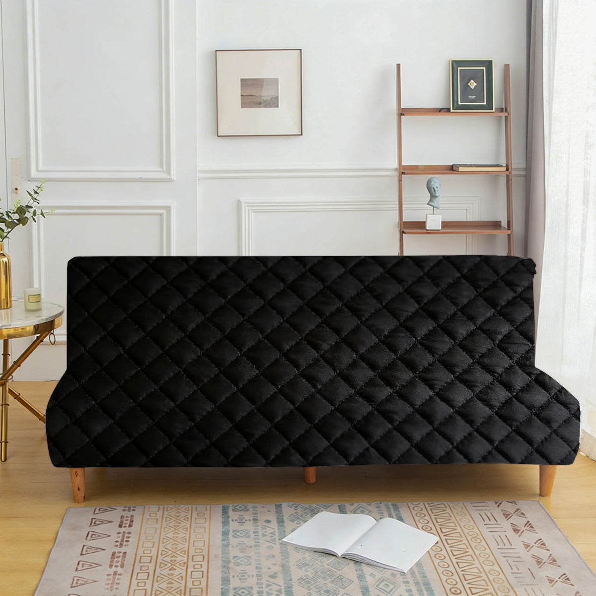 A black velvet non-slip armless sofa cover displayed on a wooden floor with an oriental rug.