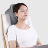 A woman is resting her head on a gray memory foam U-shaped travel neck pillow in a white chair.