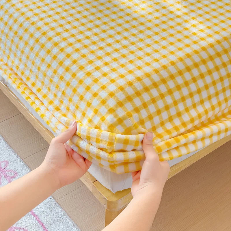 A yellow and white checkered flannel fitted sheet being folded or gathered.