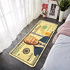 A yellow decorative floor mat featuring a portrait of Donald Trump and various currency notes.