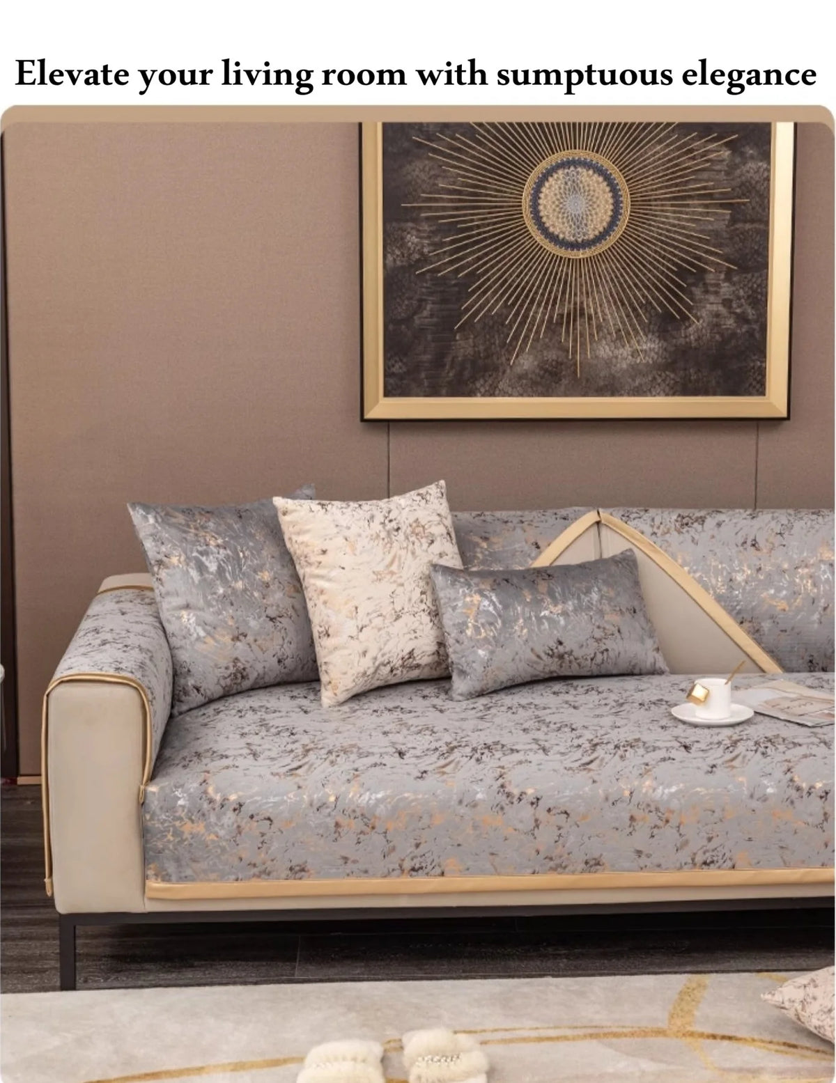 A luxurious sofa with light gray velvet cushion covers featuring gold foil accents, set against a neutral wall and framed art