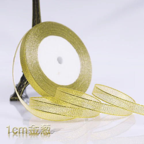 A roll of gold glitter organza ribbon lying on a white surface.