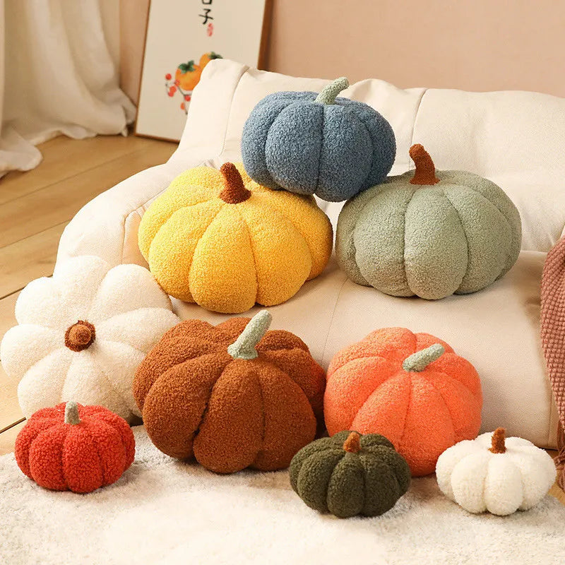 A collection of soft, fuzzy plush pumpkins in various shades of orange, green, and yellow arranged on a white surface.
