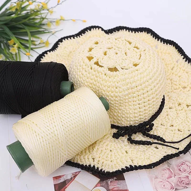 A spool of cream-colored crochet ice rope yarn next to a black yarn skein and a finished crocheted mat.