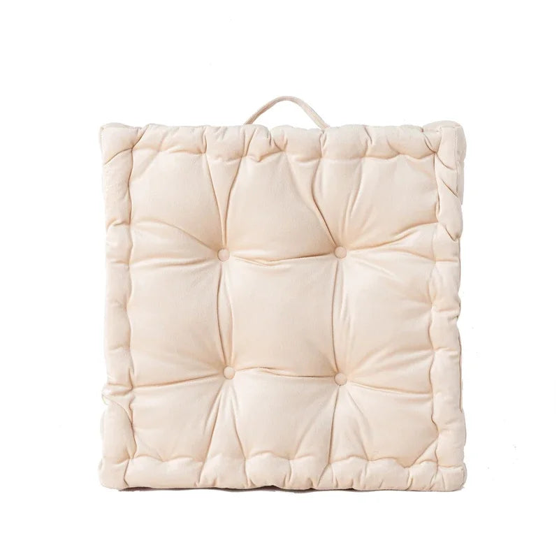 A square, light beige cotton throw pillow with a quilted texture.