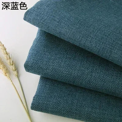 Stack of dark teal coarse linen and cotton fabric rolls