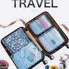 A brown travel organizer bag containing six folded pieces of light blue and pink clothing.