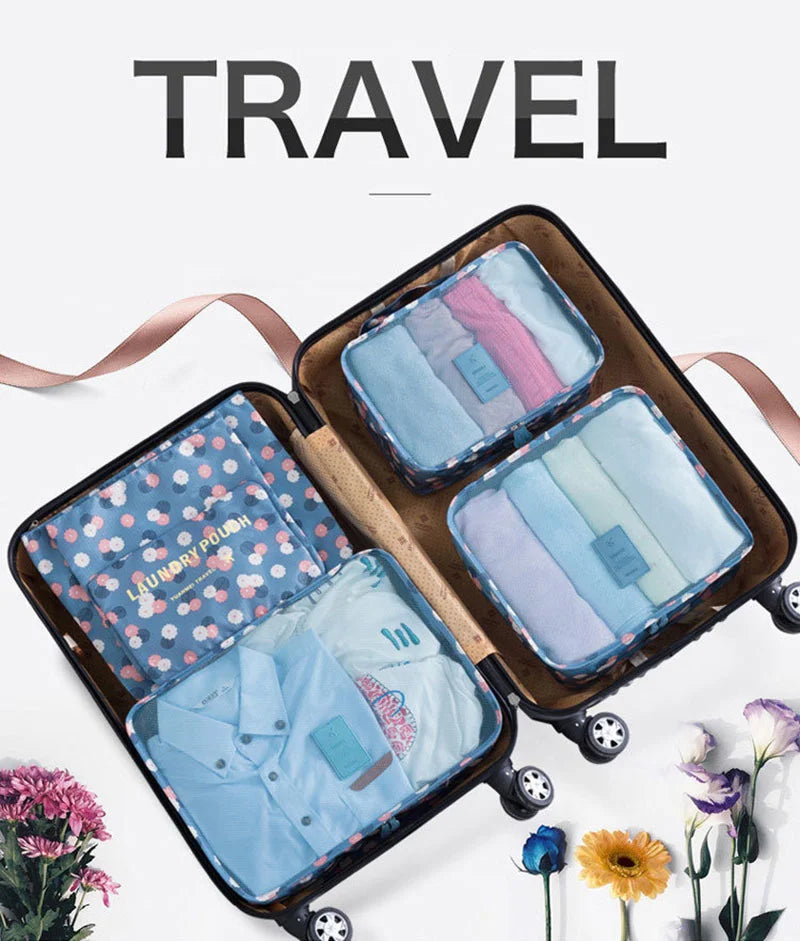 A brown travel organizer bag containing six folded pieces of light blue and pink clothing.